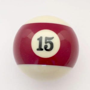 May include: A smooth, spherical billiard ball featuring a glossy finish. The ball has a wide, maroon-colored band encircling its center, which contains a white circular patch displaying the black number 15. The top and bottom sections are white.