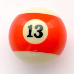 May include: A billiard ball with a smooth, glossy finish. The ball features a wide, horizontal orange stripe encircling the center, with a white circular field containing the black number 13 printed in a bold, sans-serif font on the front.