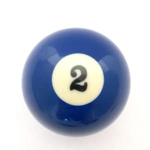 May include: A smooth, spherical billiard ball with a glossy dark blue finish. Centered on the ball is a white circular field containing the number 2 printed in a bold, black, stylized font. The object has a reflective surface and uniform shape.