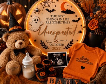 May include: A round wooden sign with LED lighting, a teddy bear wearing a witch hat, a baby bottle, knitted pumpkin booties, an ultrasound image, an orange onesie with Baby Williamson text, and four blocks spelling BABY, all arranged for a pregnancy announcement.