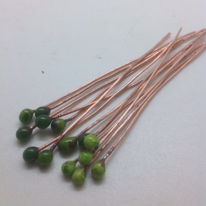 May include: A bunch of copper wire with green glass beads on the ends. The wire is about 10 cm long.