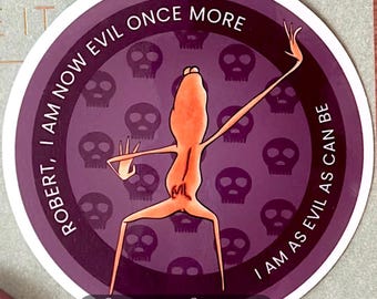 May include: A round sticker with a purple background featuring a cartoon frog in an orange color. The sticker has the text "ROBERT, I AM NOW EVIL ONCE MORE" and "I AM AS EVIL AS CAN BE". The sticker also has a signature and the shop's name.