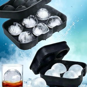 Puede incluir: Una cubitera de silicona negra con seis cavidades circulares para crear bolas de hielo esféricas. El juego incluye una tapa a juego, y la imagen muestra varias esferas de hielo transparentes en la bandeja y un vaso con líquido ámbar.
