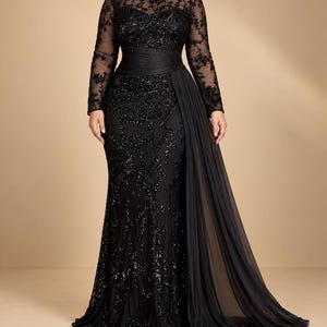May include: A floor-length black gown featuring long sheer sleeves with intricate floral embroidery and sequins. The bodice and skirt are adorned with matching black sequined patterns, a defined waistline, and a flowing side panel of sheer fabric.