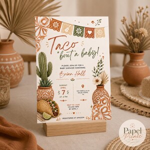 May include: A rectangular baby shower invitation card featuring the text Taco 'bout a baby! with illustrations of a cactus in a patterned pot, a taco with a lime wedge, and floral arrangements. The design includes festive bunting and event details.