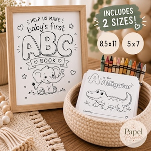 以下が含まれることがあります： HELP US MAKE baby's first ABC BOOKと象のイラストが描かれた木製フレームの看板。隣には、クレヨンとA is for Alligatorと書かれた塗り絵が入った編み込みバスケットが置かれています。