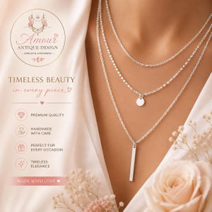 May include: A layered silver-tone necklace featuring three delicate chains. The middle chain includes a small circular pendant, while the longest chain features a vertical rectangular bar pendant. The design is simple, metallic, and minimalist.