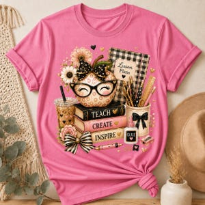 May include: A bright pink t-shirt featuring a graphic of a leopard print apple wearing black glasses, stacked books labeled Teach, Create, and Inspire, a plaid notebook labeled Lesson Plans, a coffee cup, glue, and school supplies.