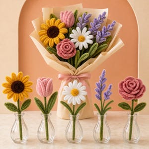 May include: A bouquet of crocheted flowers wrapped in beige paper with a pink ribbon, featuring a yellow sunflower, pink tulip, white daisy, and purple lavender. Five individual crocheted flowers in clear glass vases stand in front.