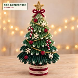 Pode incluir: Uma árvore de Natal decorativa feita de limpadores de cachimbo verdes e brancos, com uma estrela dourada no topo, um laço vermelho, enfeites de bengala doce, flocos de neve brancos e pequenos pompons vermelhos. Base listrada de vermelho e branco. Texto: PIPE CLEANER TREE PDF PATTERN.