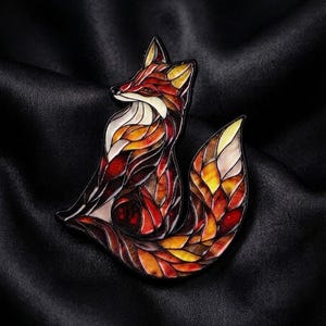 May include: A fox-shaped brooch featuring a stained-glass style design with segmented sections in shades of orange, red, yellow, and cream, outlined in black. The text PREMIUM ADORNMENTS crafted for the once in a lifetime moments is visible.