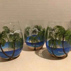 Beach, palm trees, water painted on stemless wine glasses. Hand painted.