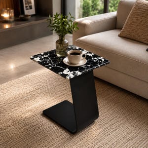 Top view of handcrafted marble side table with polished natural marble surface, coffee cup and decorative plant, luxury living room furniture, modern marble coffee table, elegant sofa end table for contemporary homes.