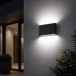 Peut inclure: Une applique murale rectangulaire noire aux bords arrondis, émettant une lumière blanche vive depuis les bords supérieur et inférieur, créant un motif d'éclairage à double faisceau sur la surface plane du mur extérieur.