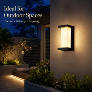 May include: A rectangular wall-mounted outdoor light fixture with a black frame and a central frosted white glass panel emitting a warm glow. The text "Ideal for Outdoor Spaces" and "Garden • Balcony • Driveway" is printed in the upper left corner.