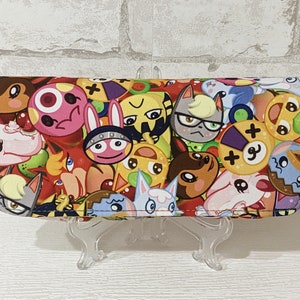 May include: A colorful wallet with a variety of animal characters, including a fox, a cat, a dog, and a squirrel. The wallet is made of fabric and has a zipper closure.