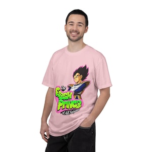May include: A light pink short-sleeved t-shirt featuring a graphic of the anime character Vegeta in battle armor. Below the character, the text reads The Fresh Prince of All Saiyans in bright green letters with a pink outline on a pink background.
