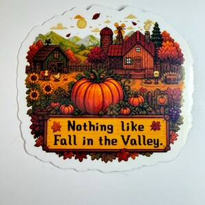 May include: A die-cut sticker featuring a pixel art farm scene during autumn. The image shows a large orange pumpkin, a wooden farmhouse, a barn, sunflowers, and trees with fall foliage. A yellow sign at the bottom reads, Nothing like Fall in the Valley.
