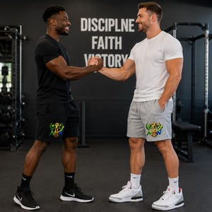 May include: A pair of black athletic shorts and a pair of light gray athletic shorts, both featuring a colorful graphic print of a fist and the letters NOW on the lower left leg, designed for active movement and gym training sessions.