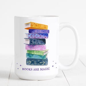 May include: White ceramic mug with a stack of colorful books and the text "BOOKS ARE MAGIC" printed on the front.