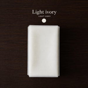 May include: A rectangular piece of light ivory fabric folded into a neat stack. Above the fabric, the text reads Light ivory in a serif font, followed by the text LIGHT IVORY in a sans-serif font and a small light ivory circular icon.
