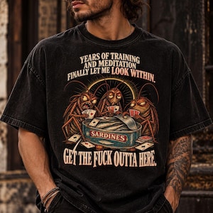 Op de afbeelding: Een zwart t-shirt met korte mouwen en een afbeelding van drie kakkerlakken die kaarten rond een open blikje sardines. De tekst luidt: YEARS OF TRAINING AND MEDITATION FINALLY LET ME LOOK WITHIN. SARDINES. GET THE FUCK OUTTA HERE.