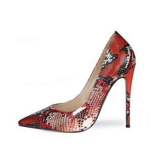 May include: A high-heeled pump shoe featuring a pointed toe and a stiletto heel. The exterior surface is covered in a textured snakeskin pattern with a color palette consisting of vibrant red, black, white, and subtle grey tones throughout.
