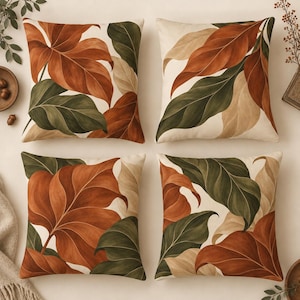 May include: A set of four square throw pillows featuring a botanical print of large leaves in shades of burnt orange, deep forest green, and cream. The pattern displays overlapping foliage across the fabric surface of each cushion.