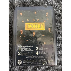 May include: A black 8-track tape for the album Mixed Emotions by the band Exile. The front label features a group photograph of the band members, the title EXILE in a gold box, and a tracklist including songs like Kiss You All Over.