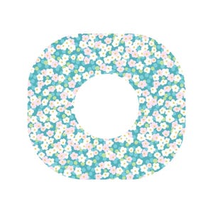 May include: A square-shaped patch with rounded corners and a circular cutout in the centre, featuring a teal background patterned with small white and light pink flowers, along with tiny yellow dots scattered throughout the floral design.
