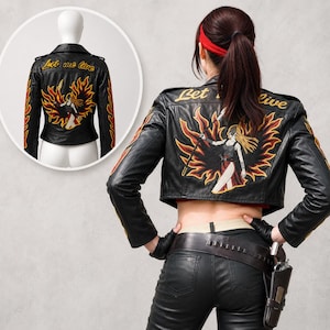 May include: A black leather cropped jacket featuring an embroidered graphic on the back of a winged figure holding a staff amidst flames, with the text Let me live in yellow script. The sleeves are decorated with embroidered orange and red flames.