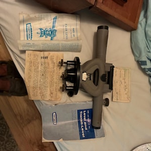 May include: A grey Craftsman farm level and transit-level tool with a black base and adjustment knobs. The set includes two printed instruction manuals and a small paper tag with the number 8997, all arranged on a white surface.