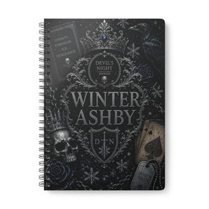 May include: A spiral-bound notebook with a black cover featuring silver illustrations of a crown, a skull, a raven, playing cards, and snowflakes. The text reads "LOYALTY. STRENGTH. ICE. VENGEANCE.", "DEVIL'S NIGHT MMXXIII", "WINTER ASHBY", and "D N".