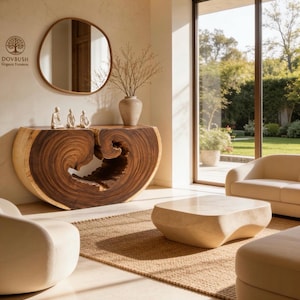 May include: A live-edge wood console table with a natural dark brown grain and a hollow center, positioned against a wall with a round mirror, a ceramic vase with branches, and three small white figurines. The text DOVBUSH Organic Furniture is visible.