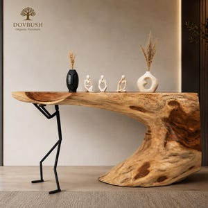 May include: A console table featuring a natural live-edge wood slab top supported by a thick, organic wood base on one side and a black metal stick-figure frame on the other. The table holds a black face vase, three small figurines, and a white vase.