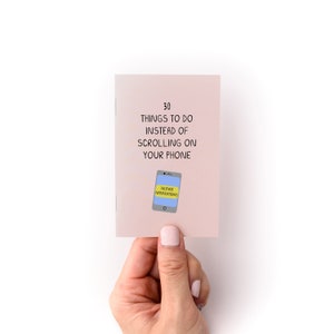 May include: A pink booklet with the text "30 THINGS TO DO INSTEAD OF SCROLLING ON YOUR PHONE" and a cartoon illustration of a smartphone with a yellow sticky note that says "SILENCE NOTIFICATIONS".