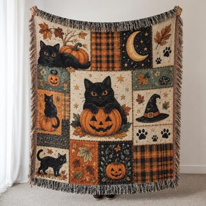 May include: A woven throw blanket featuring a patchwork design with black cats, orange pumpkins, a crescent moon, a witch hat, and autumn leaves. The blanket has a fringed edge and a color palette of black, orange, brown, and cream throughout.