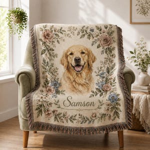 Personalized dog portrait blanket draped over green accent chair with floral border, fringe edge, and pet name Samson.