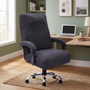 May include: A dark gray office chair featuring a textured waffle-knit fabric cover that extends over the backrest, seat, and armrests. The chair is supported by a silver-toned metal base with five black caster wheels for mobility and rotation.