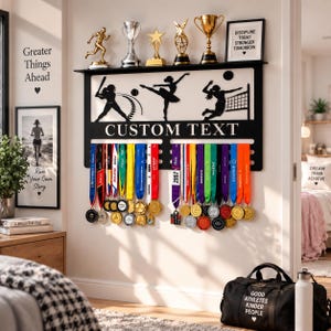 Könnte beinhalten: Ein schwarzes Wandregal aus Metall mit Silhouetten eines Baseballspielers, einer Ballerina und eines Volleyballspielers. Das Regal bietet Platz für Trophäen und Haken für Medaillen, mit dem in Weiß gedruckten Text CUSTOM TEXT.
