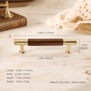 Puede incluir: Un tirador de mueble con centro de madera de nogal marrón oscuro y extremos de metal dorado cepillado. Dimensiones: 127 mm de largo, 15 mm de ancho y 32 mm de alto. La distancia entre orificios es de 96 mm. Peso: 72 g. Material: aleación de zinc y nogal.