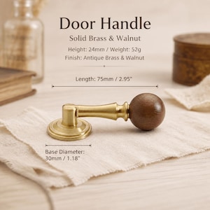 May include: A door handle made of solid brass and walnut with an antique brass finish. The handle features a round wooden knob and a circular base. Text indicates a height of 24mm, weight of 52g, a length of 75mm (2.95 inches), and a base diameter of 30mm (1.18 inches).