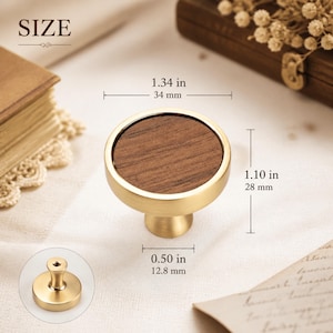 May include: A round cabinet knob featuring a brushed gold metal frame and a circular dark wood inlay. The knob measures 1.34 inches in diameter, 1.10 inches in height, and has a base diameter of 0.50 inches as indicated by the visible dimension text.