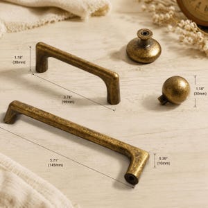 May include: Two antique brass finish cabinet pulls and two matching knobs. The smaller pull measures 3.78 inches in length and 1.18 inches in height. The larger pull is 5.71 inches long. The knobs are 1.18 inches tall and 0.39 inches wide.