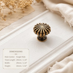 May include: A round, antique brass-finished metal cabinet knob with a fluted, petal-like design. The knob features a single hole mount with a total length of 1.14 inches, a width of 1.14 inches, and a height of 1.02 inches as indicated by the text.