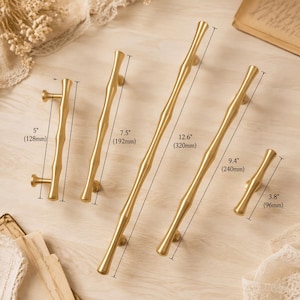 May include: Five gold-toned metal cabinet pulls with a bamboo-inspired texture. The pulls are labelled with lengths of 128mm, 192mm, 320mm, 240mm, and 96mm, each featuring two mounting posts for attachment to furniture or cabinetry doors.