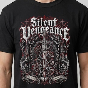 May include: A black t-shirt featuring a graphic print of a sword entwined with roses and chains. The text "Silent Vengeance" appears at the top in a gothic font, with "Pain Is Silent" and "But Vengeance Speaks" printed on a banner below.
