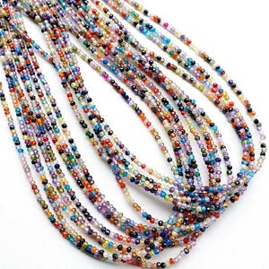 May include: A multi-strand necklace composed of numerous tiny, faceted, translucent beads in a vibrant spectrum of colours including red, blue, green, yellow, purple, and orange. The beads are arranged in long, flowing, parallel strands.