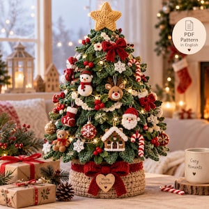 Pode incluir: Uma árvore de Natal de crochê com uma estrela amarela no topo, laços vermelhos e vários ornamentos, incluindo um boneco de neve, rena, Papai Noel, casa de gengibre e um ursinho. A base é um vaso de crochê bege com um laço vermelho.