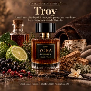 May include: A 50 mL bottle of Troy Yora Eau de Parfum with a black cap and ribbed glass base. The label reads Troy Yora Eau de Parfum 50 mL | 1.7 FL. OZ. It is surrounded by lime, black currants, peppercorns, vanilla, wood, and moss.
